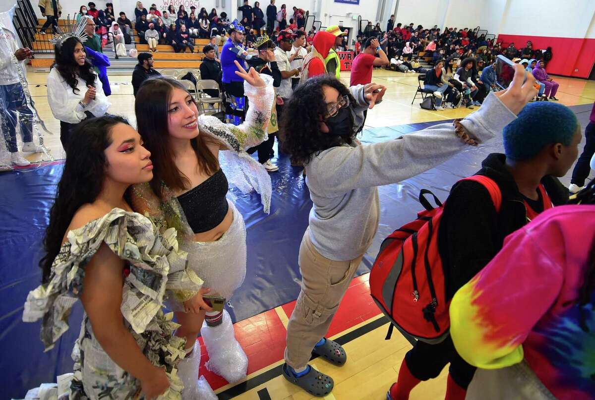 As part of J.M. Wright Technical High School's Earth Day Celebration, student Sandy Lima, right, takes a selfie with models Karla Segovia, left, and Natalie Morales Adriana, center, during its "trashy" fashion show in the gymnasium in Stamford, Conn., on Friday.