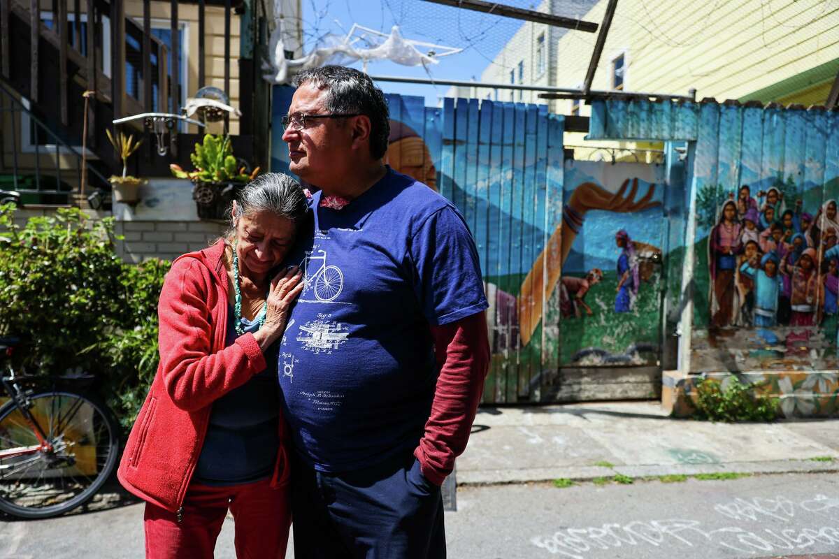Andrés Rojo (right) and friend Denhi Donis embrace outside the Balmy Alley garage where he has worked and lived.
