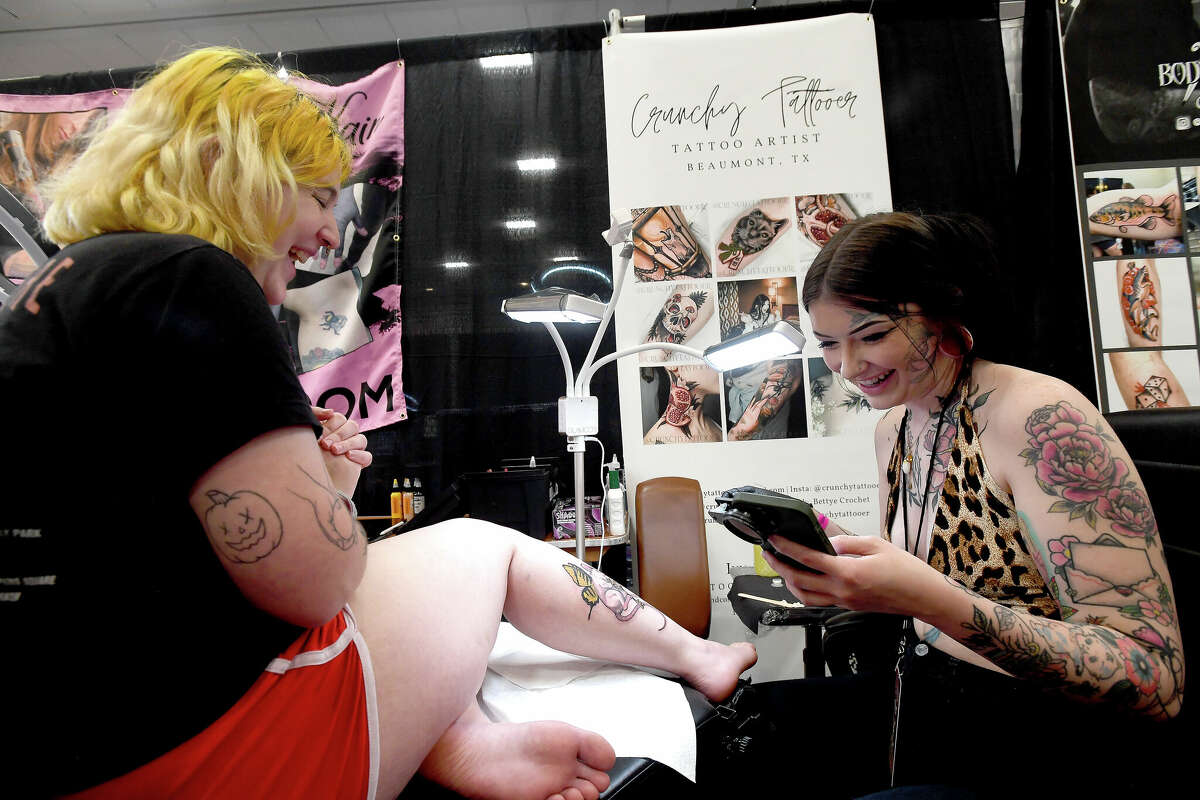 Tattooist Bettye Crochet jokes with Bethanie Smith as she works on a piece on the opening day of this Ink Masters Tattoo Convention that runs through Sunday at the MCM Elegante Hotel. Photo made Friday April 22, 2022. Kim Brent/The Enterprise