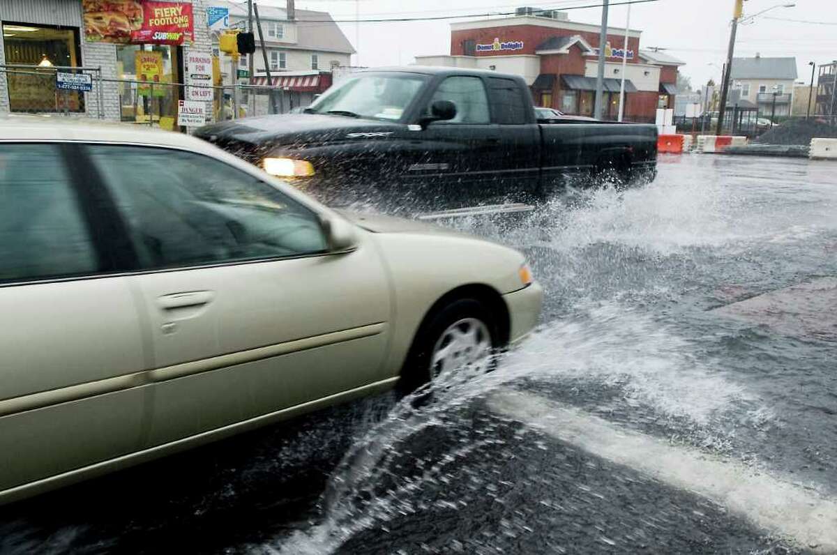 Cars plow through puddles at the corner of Myrtle Avenue and Elm Street as heavy rain falls in Stamford, Conn. on Friday October 1, 2010.
