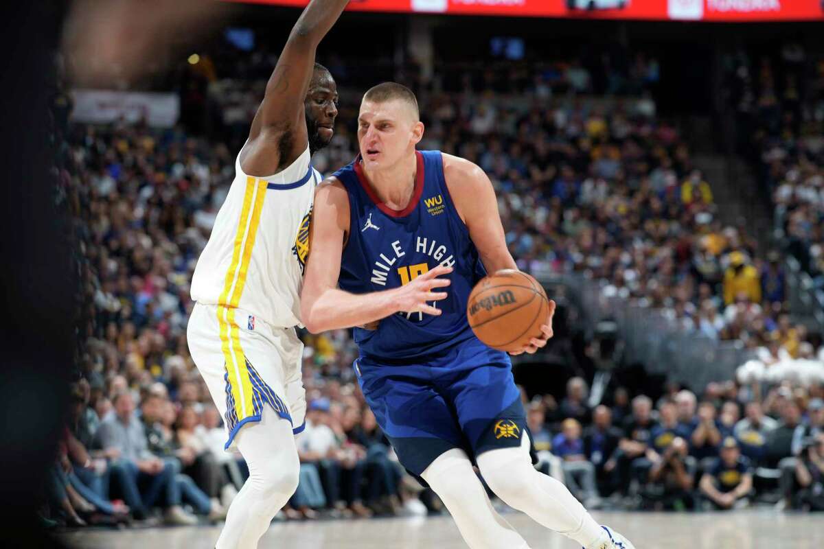 Golden State Warriors forward Draymond Green (23) and Denver Nuggets center Nikola Jokic (15) in the second half of Game 3 of an NBA basketball first-round Western Conference playoff series Thursday, April 21, 2022, in Denver. (AP Photo/David Zalubowski)