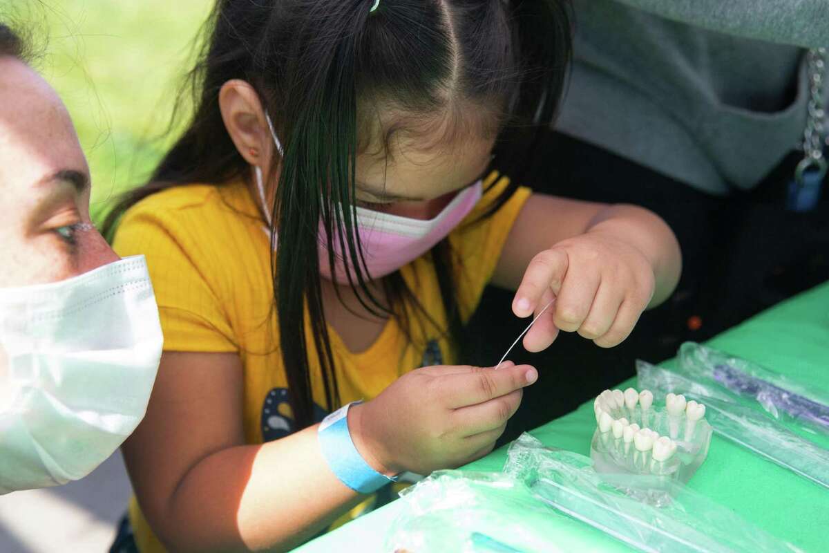 Erin Welter, a dental student from UCSF School of Dentistry, teaches Emely, 4, how to floss her teeth during the “Vidas Saludables” Community Health and Wealth Fair hosted on April 23.