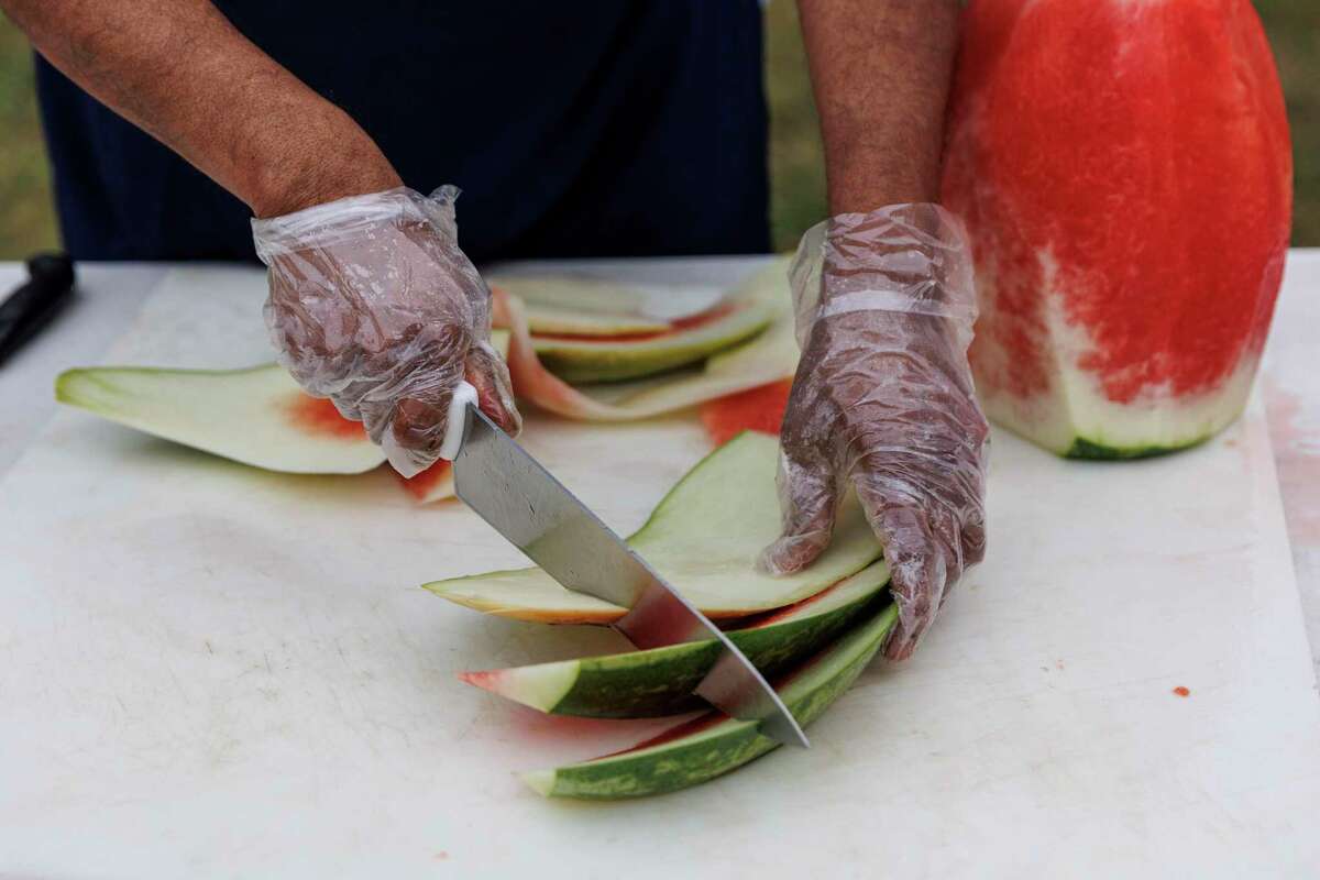 A volunteer cuts watermelon as people break the fast and celebrate Ramadan together at the Muslim Children Education and Civic Center in San Antonio on Thursday.