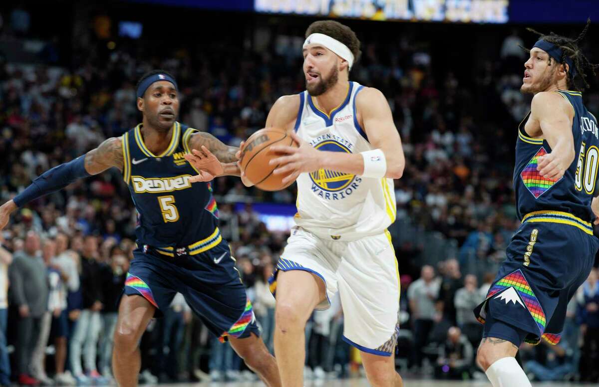 Golden State Warriors guard Klay Thompson, center, drives the lane bertween Denver Nuggets forwards Will Barton, left, and Aaron Gordon in the first half of Game 4 of an NBA basketball first-round Western Conference playoff series Sunday, April 24, 2022, in Denver. (AP Photo/David Zalubowski)