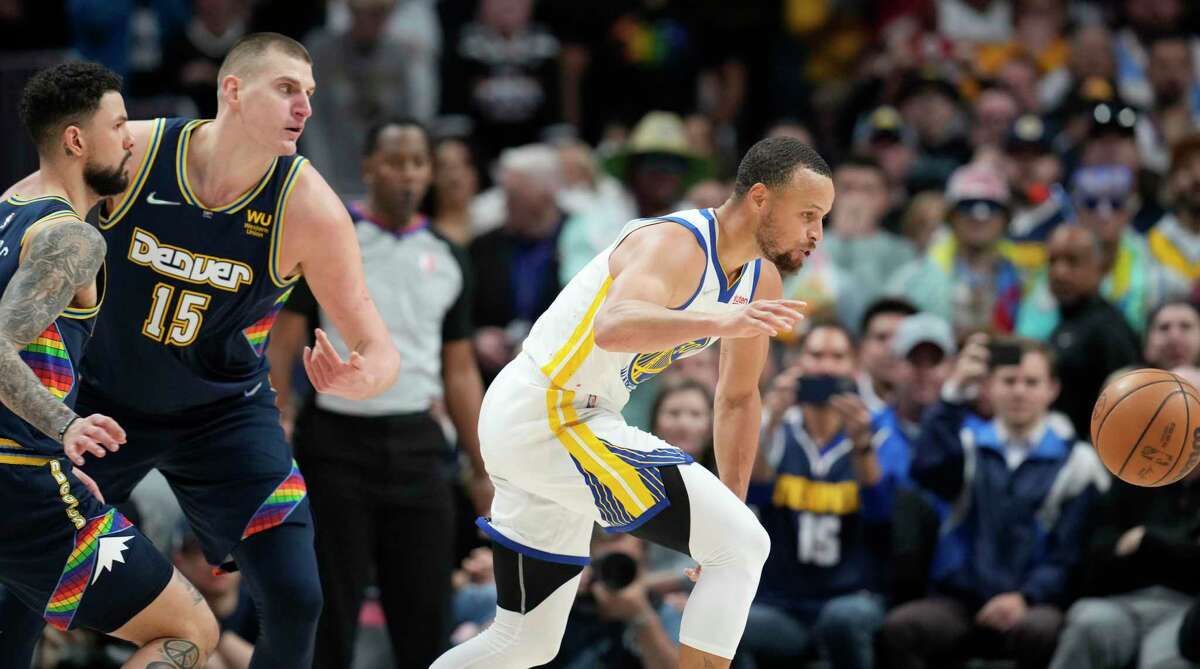 Golden State Warriors guard Stephen Curry, right, loses control of the ball after driving between Denver Nuggets guard Austin Rivers, front left, and center Nikola Jokic in the second half of Game 4 of an NBA basketball first-round Western Conference playoff series, Sunday, April 24, 2022, in Denver. (AP Photo/David Zalubowski)