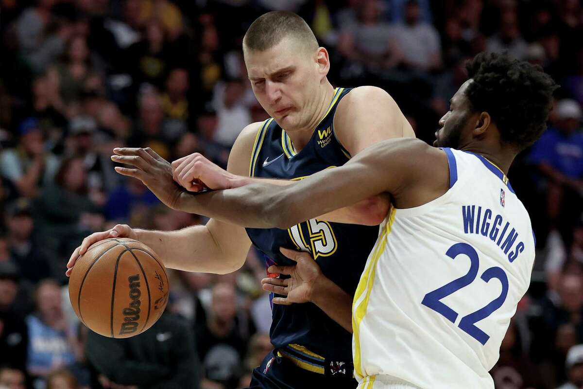 DENVER, COLORADO - APRIL 24: Nikola Jokic #15 of the Denver Nuggets drives against Andrew Wiggins #22 of the Golden State Warriors in the first quarter during Game Four of the Western Conference First Round NBA Playoffs at Ball Arena on April 24, 2022 in Denver, Colorado.