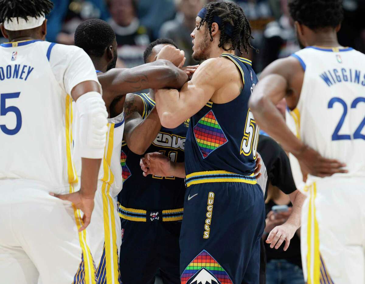 Golden State Warriors forward Draymond Green, center left, pushes Denver Nuggets forward Aaron Gordon, center right, after he was called for a foul against Nuggets center Nikola Jokic (not shown) in the first half of Game 4 of an NBA basketball first-round Western Conference playoff series Sunday, April 24, 2022, in Denver. (AP Photo/David Zalubowski)