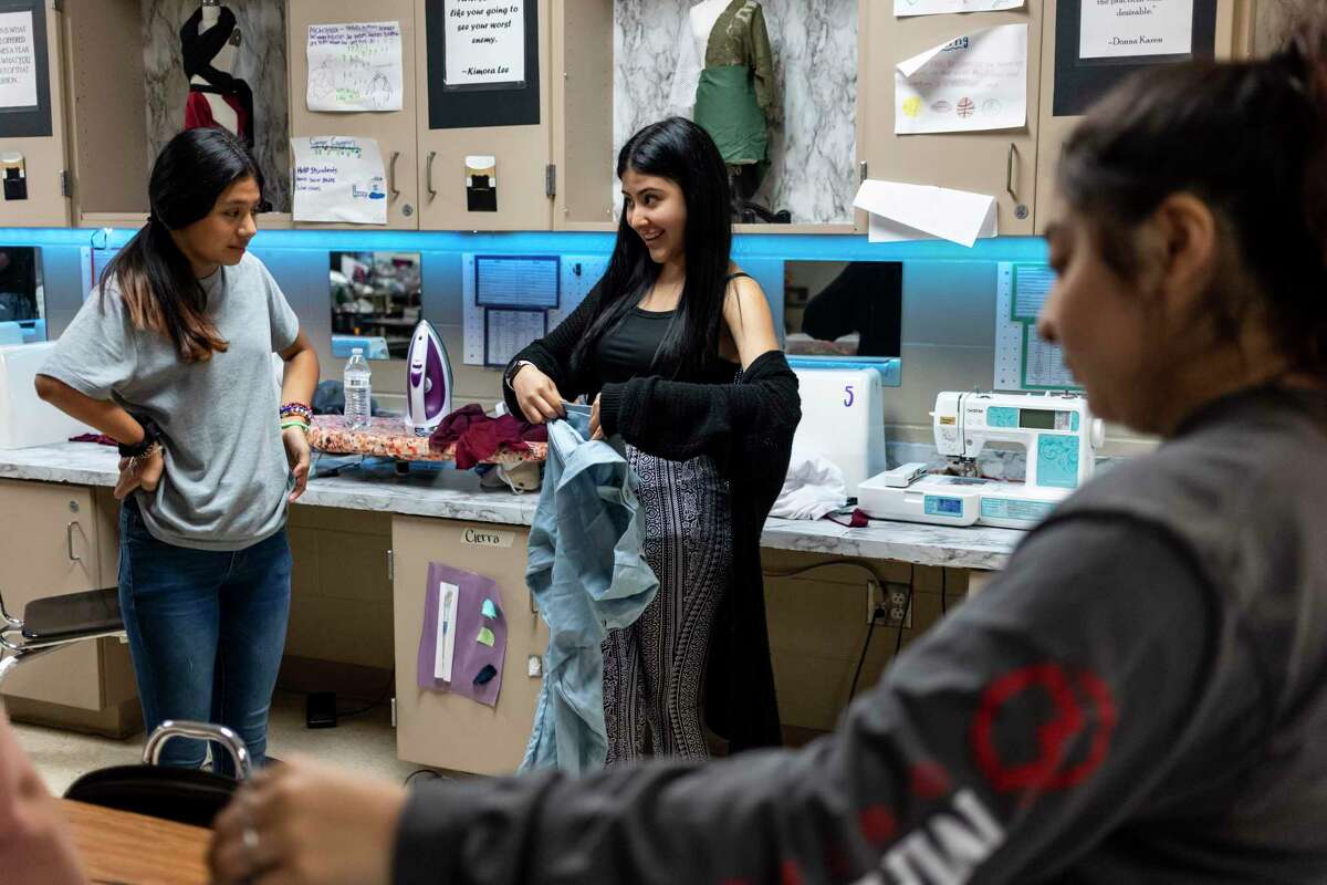 La modella Ariana Gutierrez, 12 anni, parla con la studentessa di moda Amberlyn Reyna-Martinez, 17 anni, mentre lavorano all'ensemble di Arianna per la sfilata di moda Fashion-Able alla Wagner High School di San Antonio, in Texas, il 21 aprile 2022.