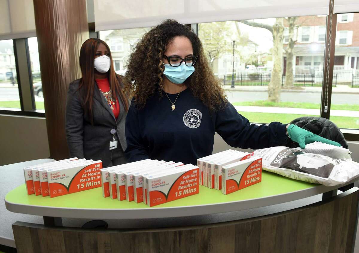 Kayla Daniels, immunization outreach worker for the New Haven Health Department, stocks a display of at-home rapid COVID-19 test kits and KN95 masks at the Stetson Library in New Haven on April 25, 2022. The City of New Haven planned to distribute 5,000 test kits and masks on Monday and Thursday, April 28, at the five branches of the New Haven Free Public Library.