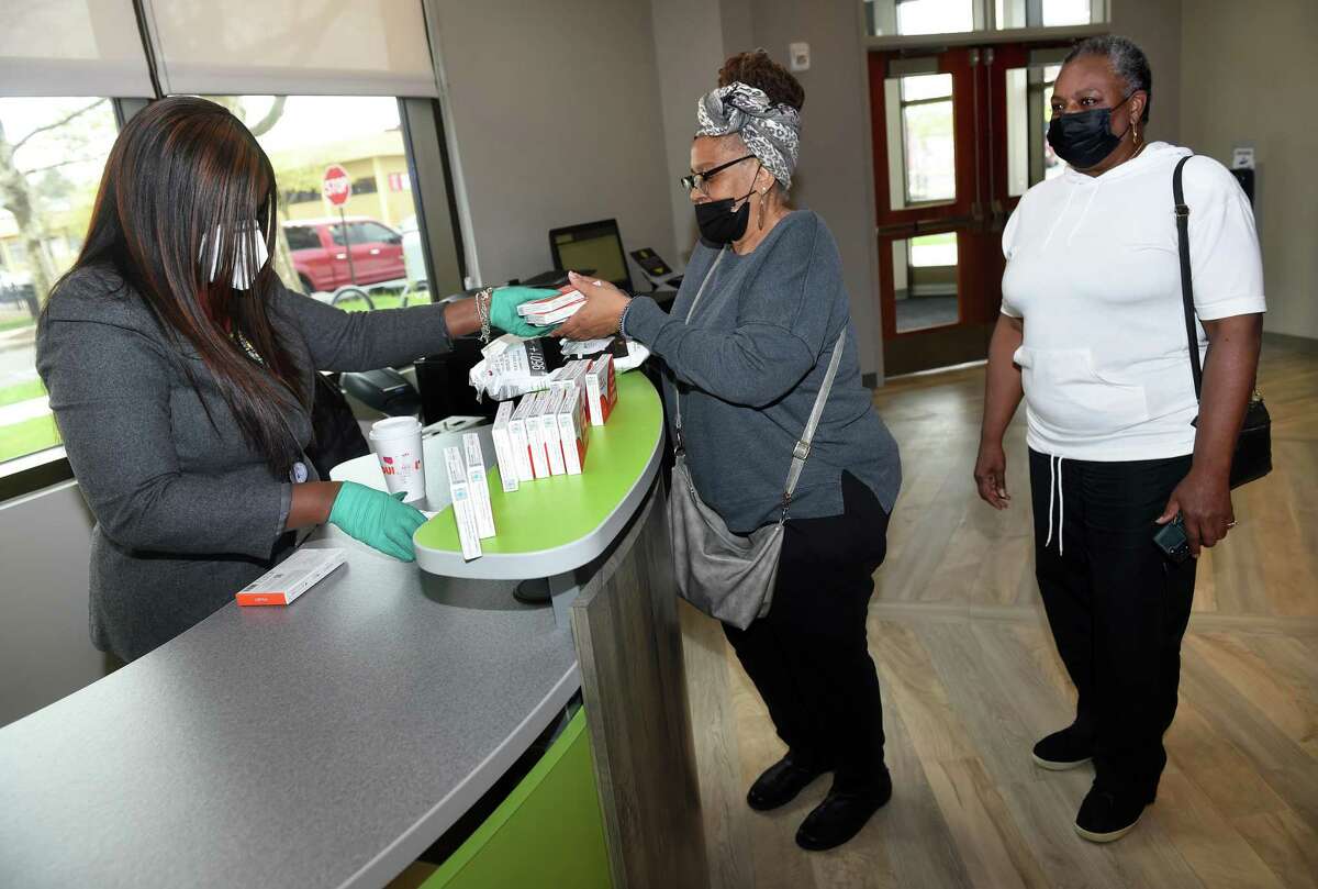 From left, Laurel Smith, project manager for the New Haven Office of Emergency Management, hands out at-home rapid COVID-19 test kits and KN95 masks to Gail Hayes and Stephanie James of New Haven at the Stetson Library in New Haven on April 25, 2022. The City of New Haven planned to distribute 5,000 test kits and masks on Monday and Thursday, April 28, at the five branches of the New Haven Free Public Library.