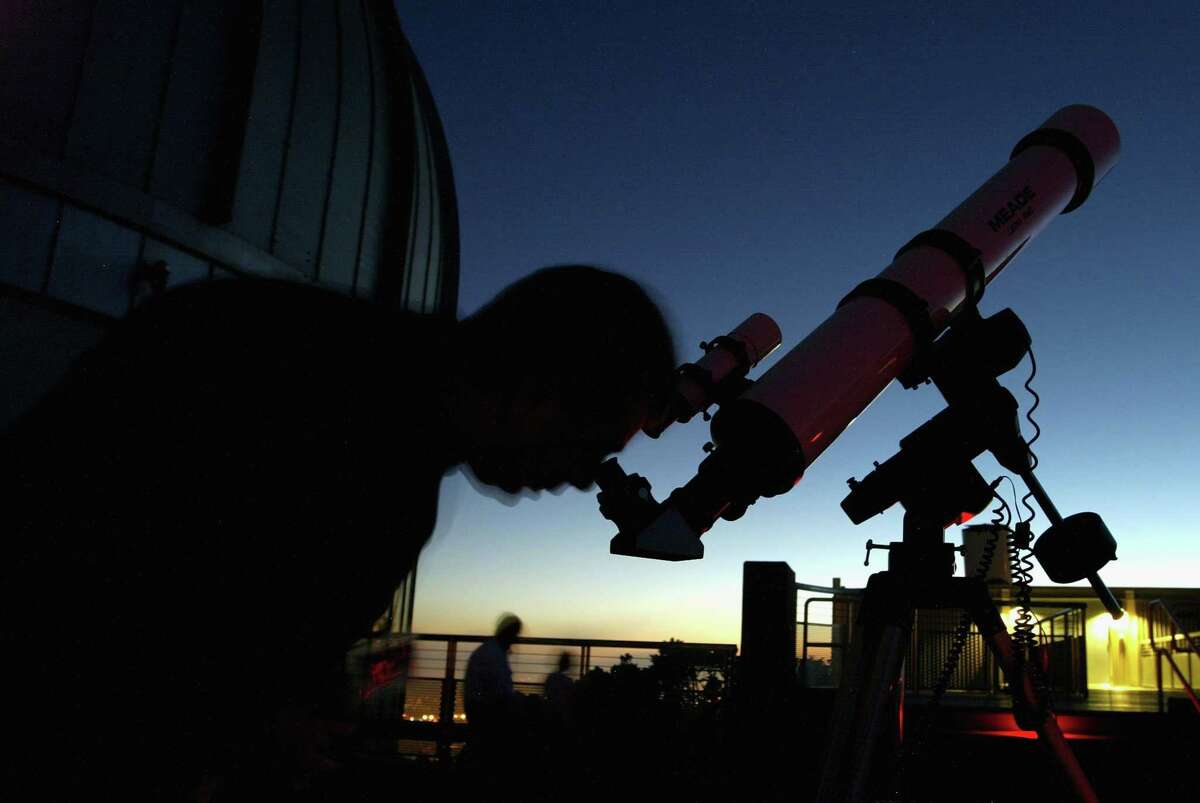 如何在海湾地区的夜空中看到哈雷彗星残骸。登录必赢亚洲一名男子在加州奥克兰市的夏博特空间科学中心通过望远镜观察。