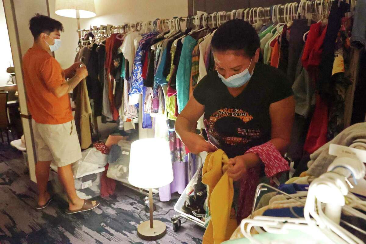 Migrants pick clothing for family at a room set up by Catholic Charities San Antonio at a hotel on Monday. The nonprofit helps migrants with lodging, food, clothing and if needed traveling fares. They also provide legal help when needed.
