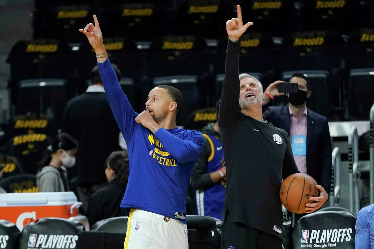 Golden State Warriors guard Stephen Curry, left, and assistant coach Bruce Fraser gesture before Game 2 of an NBA basketball first-round playoff series against the Denver Nuggets in San Francisco, Monday, April 18, 2022. (AP Photo/Jeff Chiu)