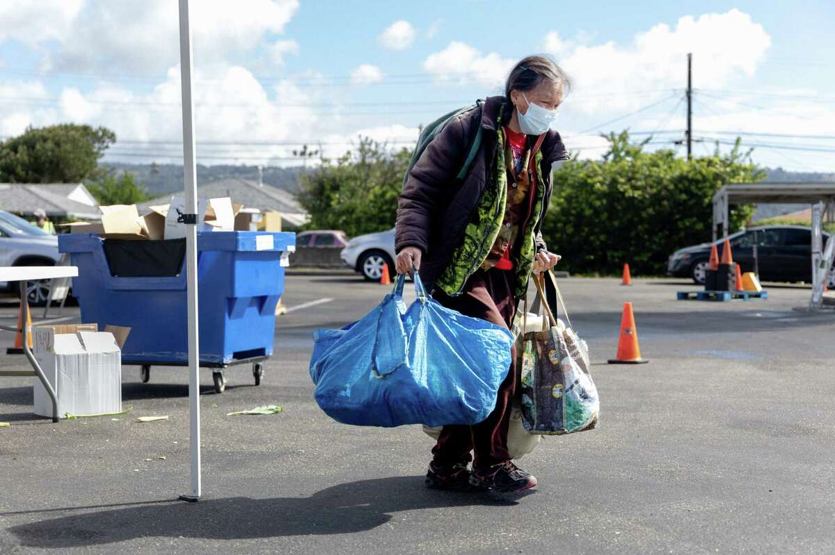A guest of the Alameda County Community Food Bank returns to her apartment following a pickup at the food bank’s remote location in Oakland on Friday, April 22, 2022. Inflation has hit lower-income earners and those on fixed incomes hard.