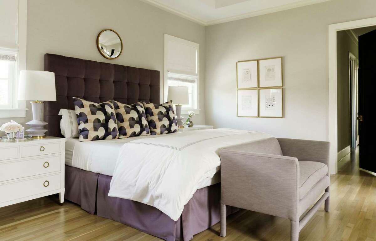 Deep lavender repeats in the primary bedroom, in the headboard, footboard bench and decorative pillows.