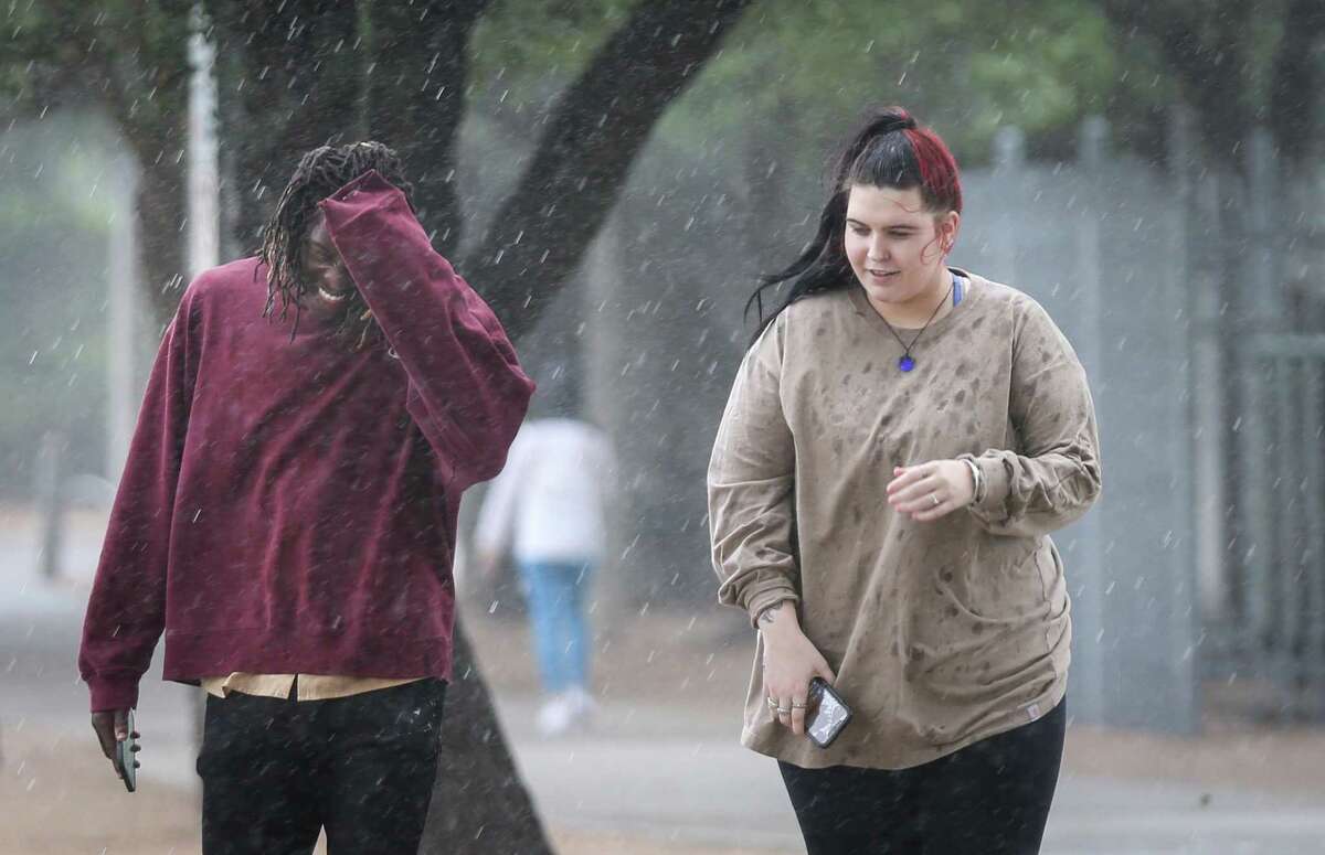 File photo from April 25, 2022 shows Deb Ren, left, and his friend Lex Ofczarzak walk to her car as rain from a cold front begins to fall at Eleanor Tinsley Park in Houston.