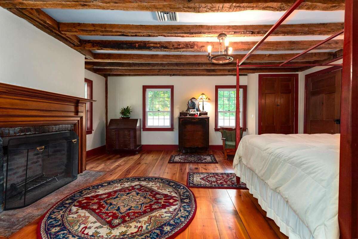 This bedroom, one of five, features wide-plank floors and fireplace.