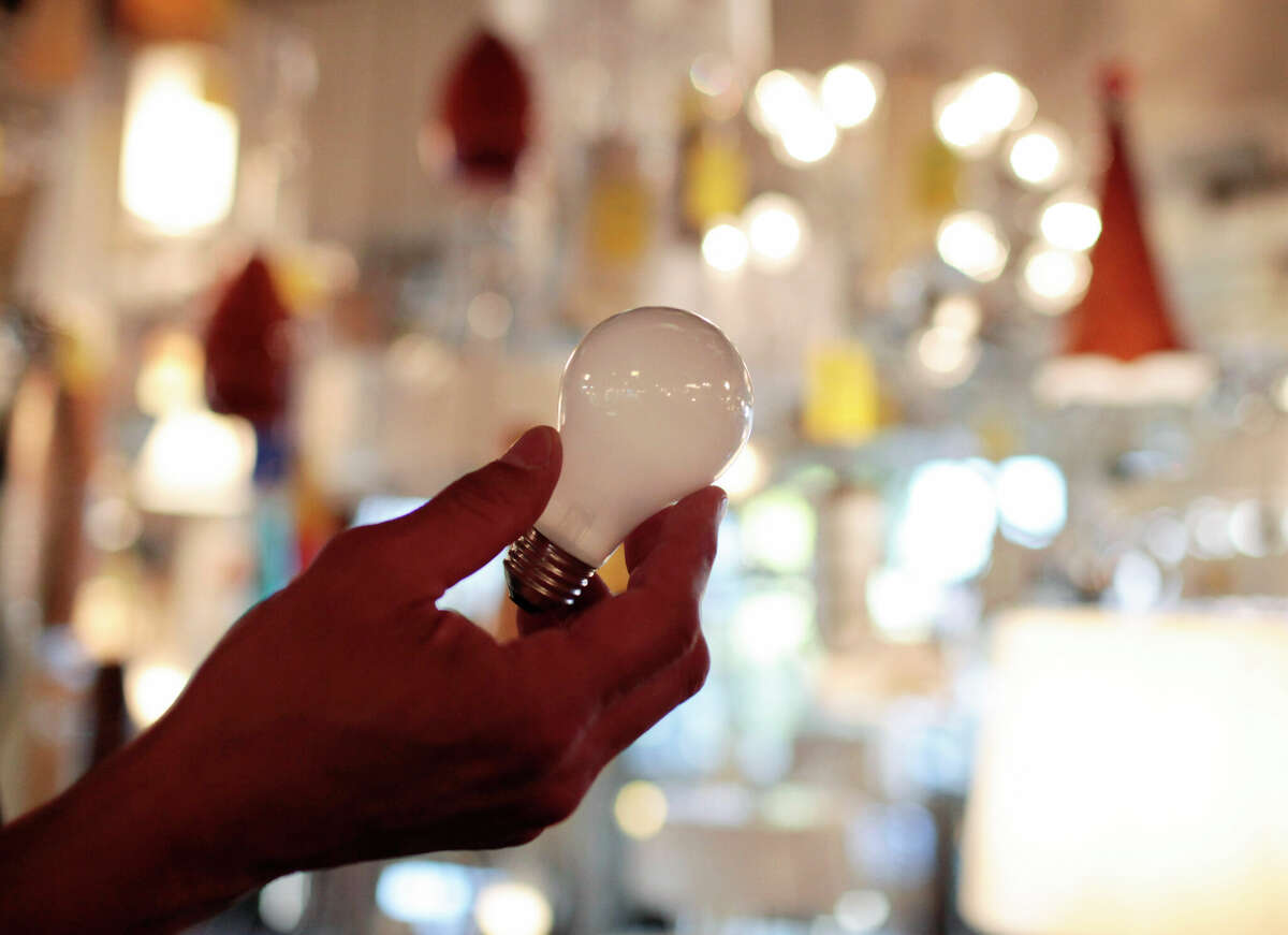 Nick Reynoza holds a 100-watt incandescent light bulb. The Biden administration is scrapping old-fashioned incandescent light bulbs, speeding an ongoing trend toward more efficient lighting.
