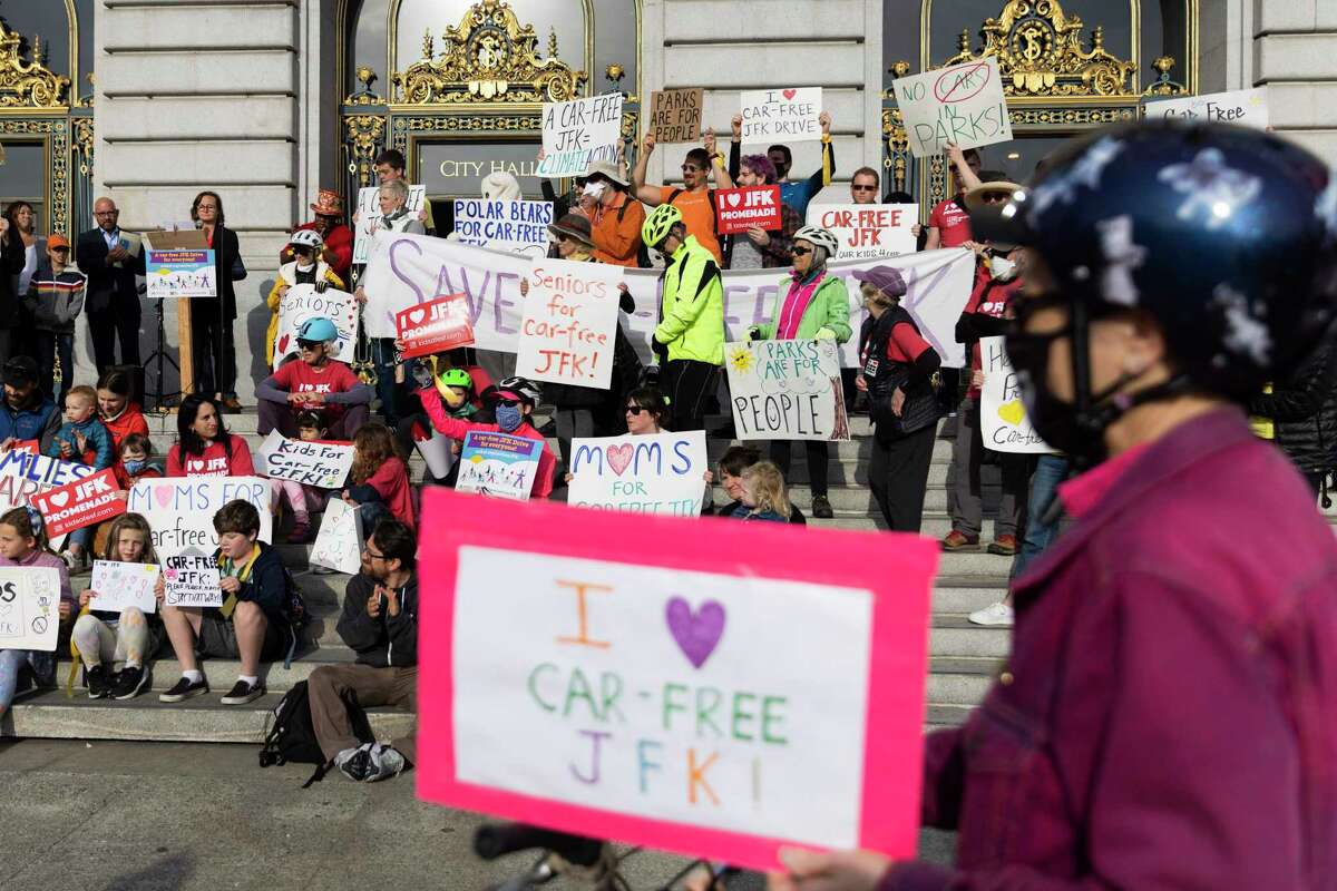 Hundreds gather and carry signs during a rally Tuesday outside of San Francisco City Hall in support of keeping the east side of Golden Gate Park's John F. Kennedy Drive permanently free of cars.