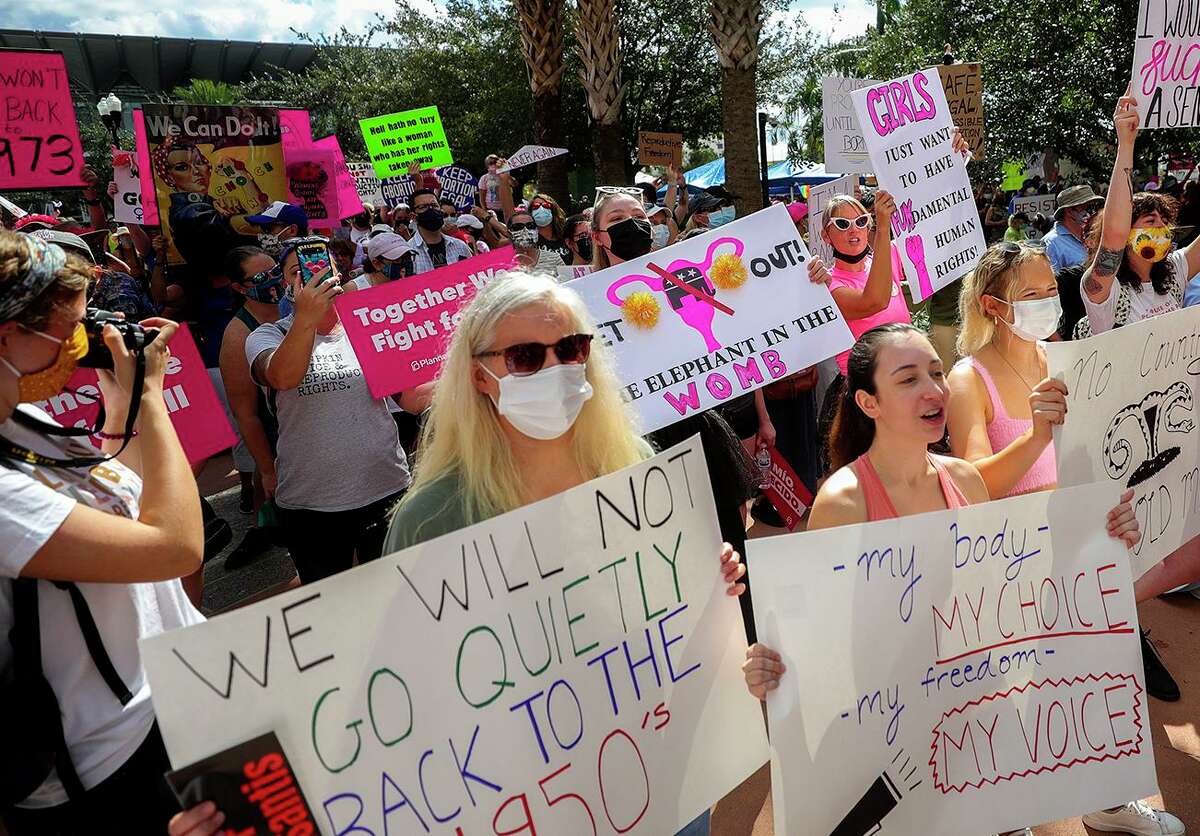 Participants wave signs as they walk back to Orlando City Hall during the March for Abortion Access on Saturday, Oct. 2, 2021, in Orlando, Fla.