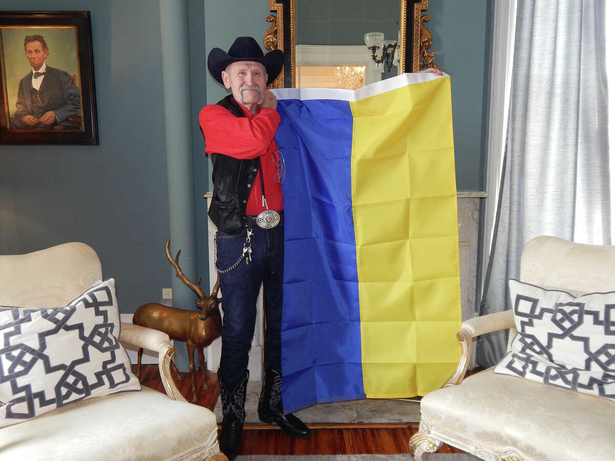 Scotty DeWolf holds a Ukrainian flag in the parlor of Villa DeWolf bed and breakfast in Jacksonville. DeWolf is hoping to convince Jacksonville residents to plant sunflowers in a show of support for the war-torn nation.