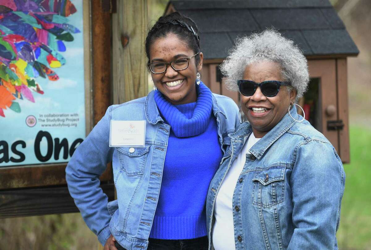 St. Joseph High School student Danielle Haniph, 17, left, poses for a photo with State Senator Marilyn Moore after unveiling her mural, “Trumbull Soars As One”, during Earth Day at the Trumbull Nature and Arts Center in Trumbull, Conn., on Saturday, April 16, 2022. The mural, along with a second to be displayed at the Trumbull Library, was created using hundreds of colorful feathers created by local students.
