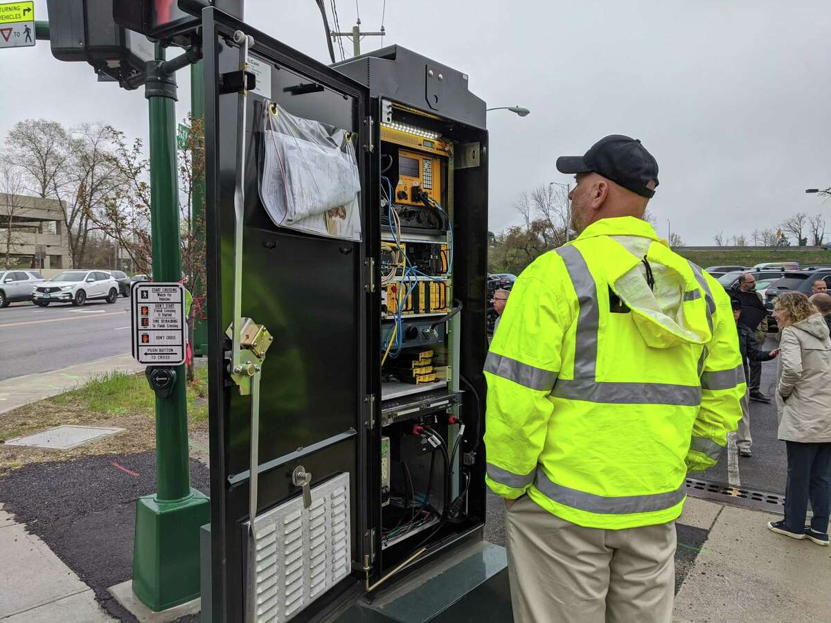 A ribbon-cutting event is held Tuesday April 26, 2022, for new traffic lights on Arch Street in downtown Greenwich. The signal boxes at each corner is used to help coordinate the network among them. Before the ribbon cutting, Sean Turpin from the town Highway Division checks out the box.