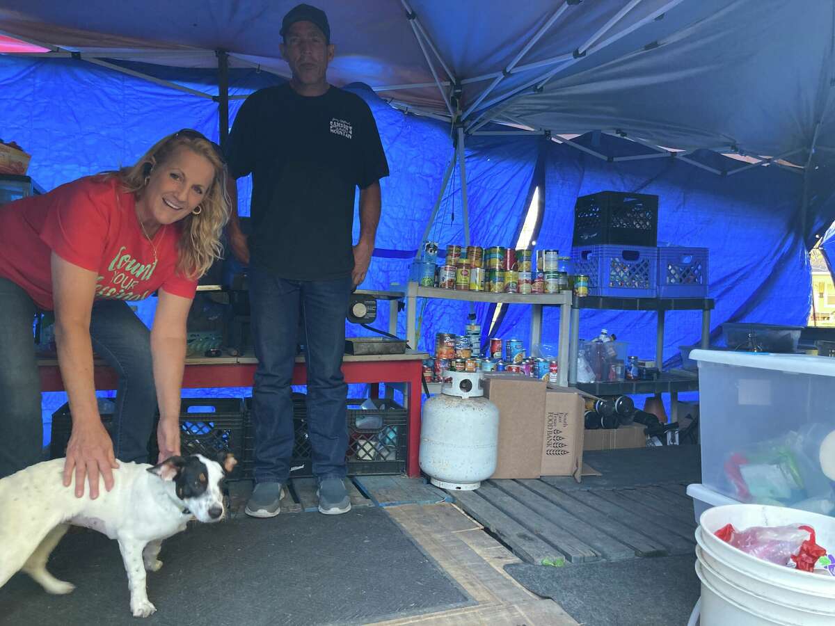 One of the seven tents is for food and supplies for the residents of the camp. Many of the food is donated by community organizations. Pictured: Diana Burnett, manager of the camp, pets Sugar, a dog recently returned to her human by non-profit Anna’s Angels, and Jimmy, a resident of the camp. 