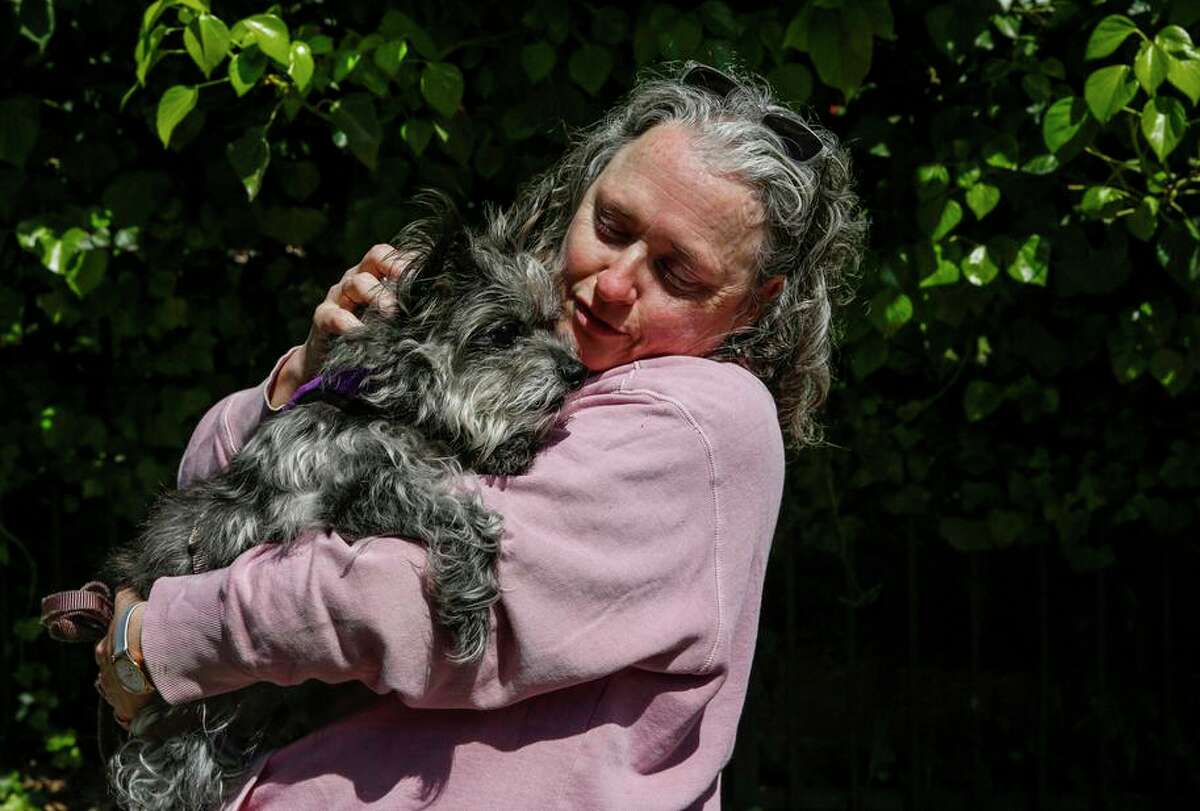 Bonnie Candell holds her senior dog Beastie, 12, outside her Oakland home. She is among hundreds of pet owners left in limbo to find pet care after an abrupt closure at Montclair Veterinary Hospital.