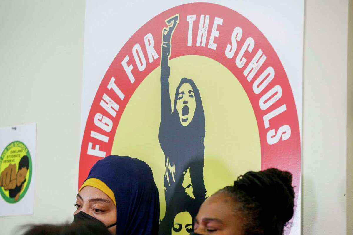 A sign can be seen behind members of OEA in a press conference denouncing the Oakland Unified School District’s decision to close schools in Oakland, Calif. on Monday, April 26, 2022.