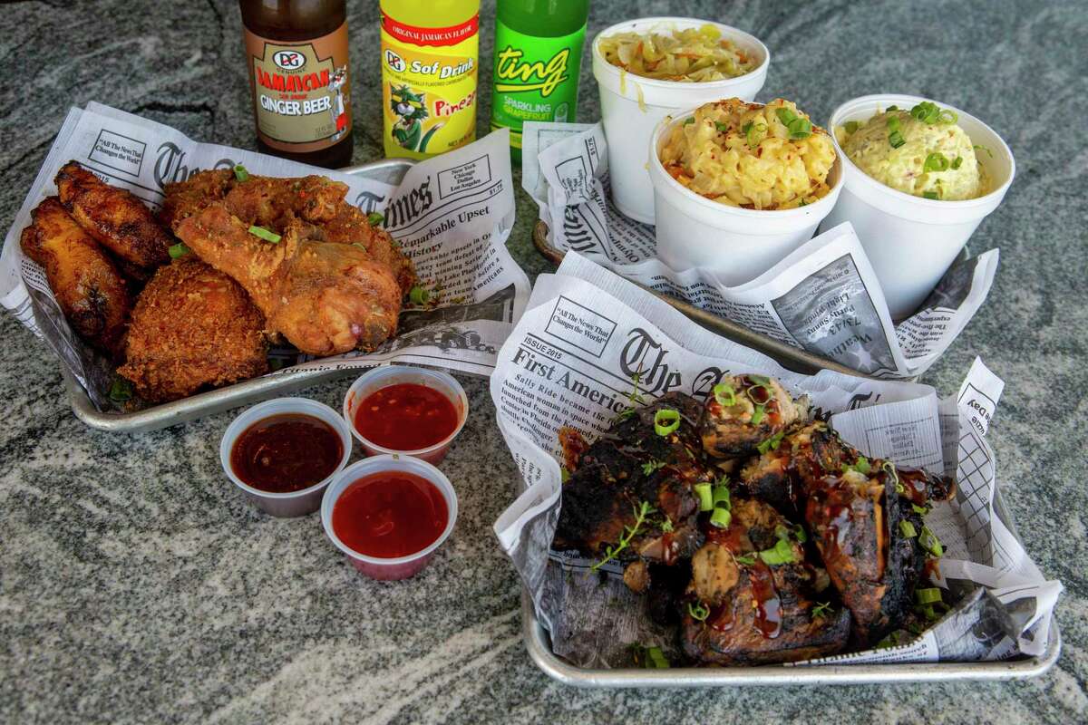 Jerk Shack fried chicken, left, and jerk chicken are seen Monday April 18, 2022 along with sides of sautéed cabbage, from left, Mac and cheese and potato salad.