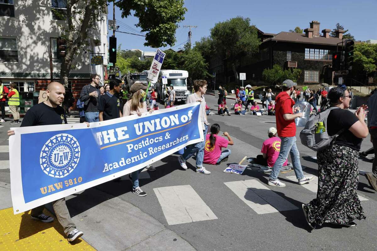 2022年4月26日，工会工人和他们的支持者在加州大学伯克利分校外的欧几里得大道和赫斯特大道的十字路口静坐抗议，阻塞了交通。数千名加州大学的学术学生工作者——助教、博士后和研究人员——在加州大学所有10个校区抗议工作条件和工资。