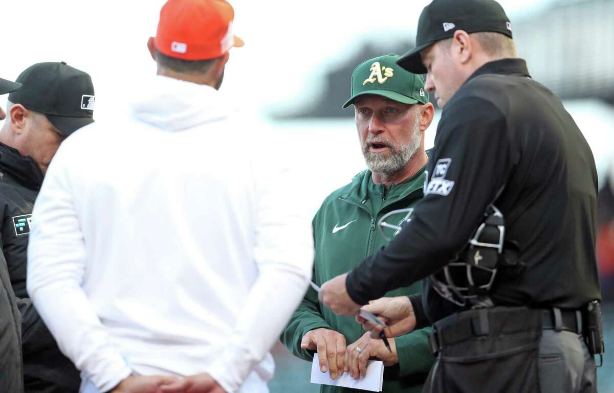Oakland Athletics’ manager Mark Kotsay and San Francisco Giants’ manager Gabe Kapler meet with umpires before Tuesday’s game at Oracle Park in San Francisco, Calif.