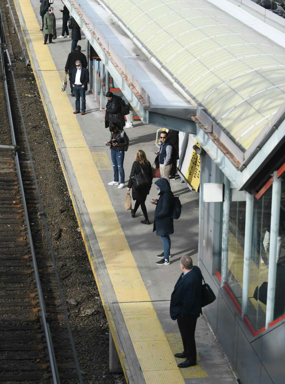 Commuters wait on the train platform during the morning rush hour at the Stamford Transportation Center in Stamford, Conn. Wednesday, March 23, 2022.