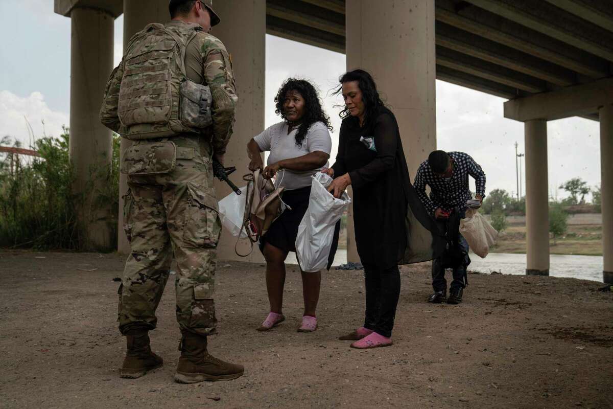 Two Nicaraguan women put their belongings in bags, waiting to be processed by Border Patrol agents after crossing the Rio Grande into Eagle Pass, Texas on Tuesday, April 5, 2022.