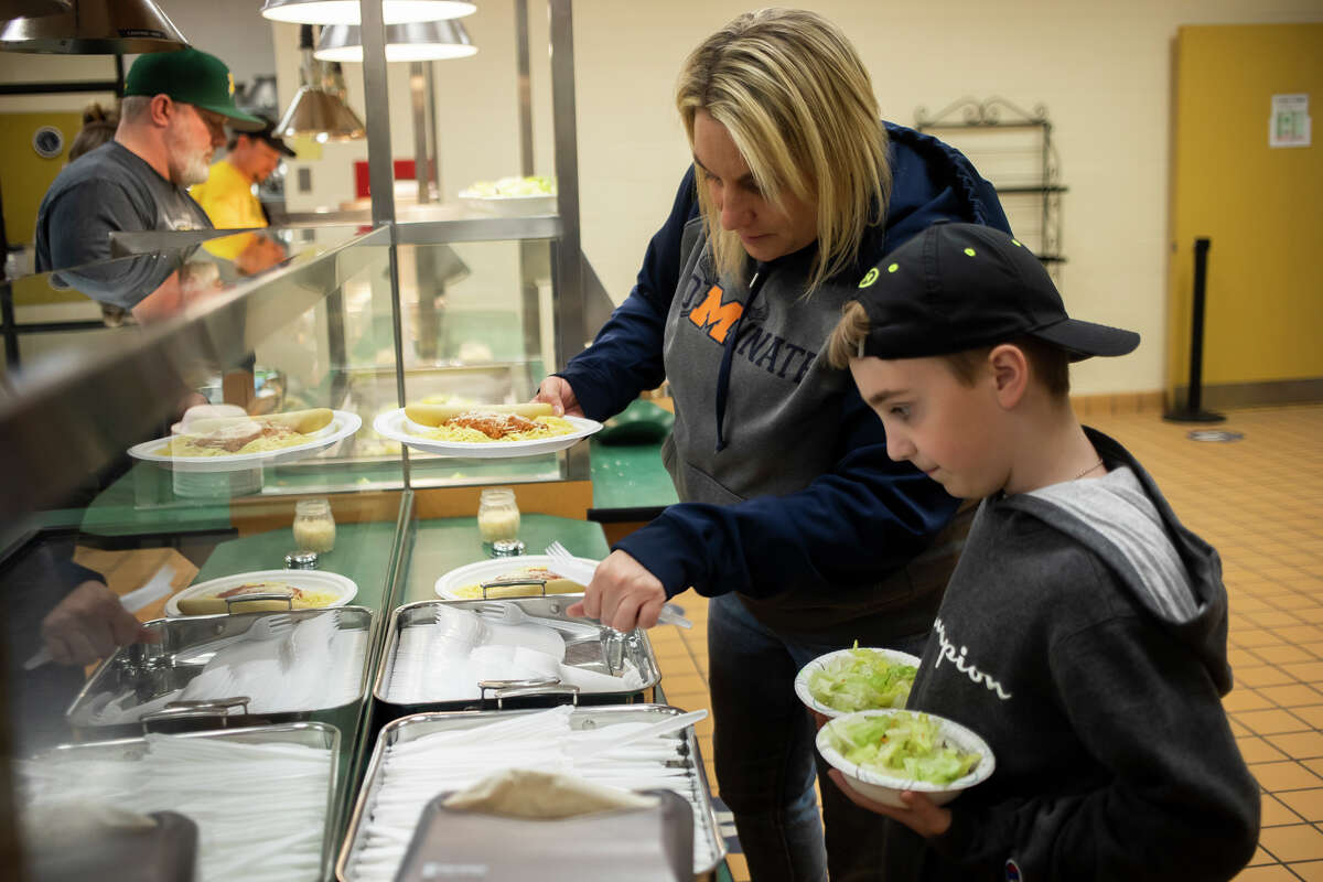 Gli allenatori Dow Excessive servono cene a base di spaghetti durante la raccolta fondi Pasta with a Objective 4 Jenni Clerc e Beau Clerc, 8 anni, vengono serviti a cena dagli allenatori Dow durante Pasta with a Purpose, un evento di raccolta fondi per il Dow High Sports Booster Club martedì 26 aprile 2022 presso la scuola di Midland.