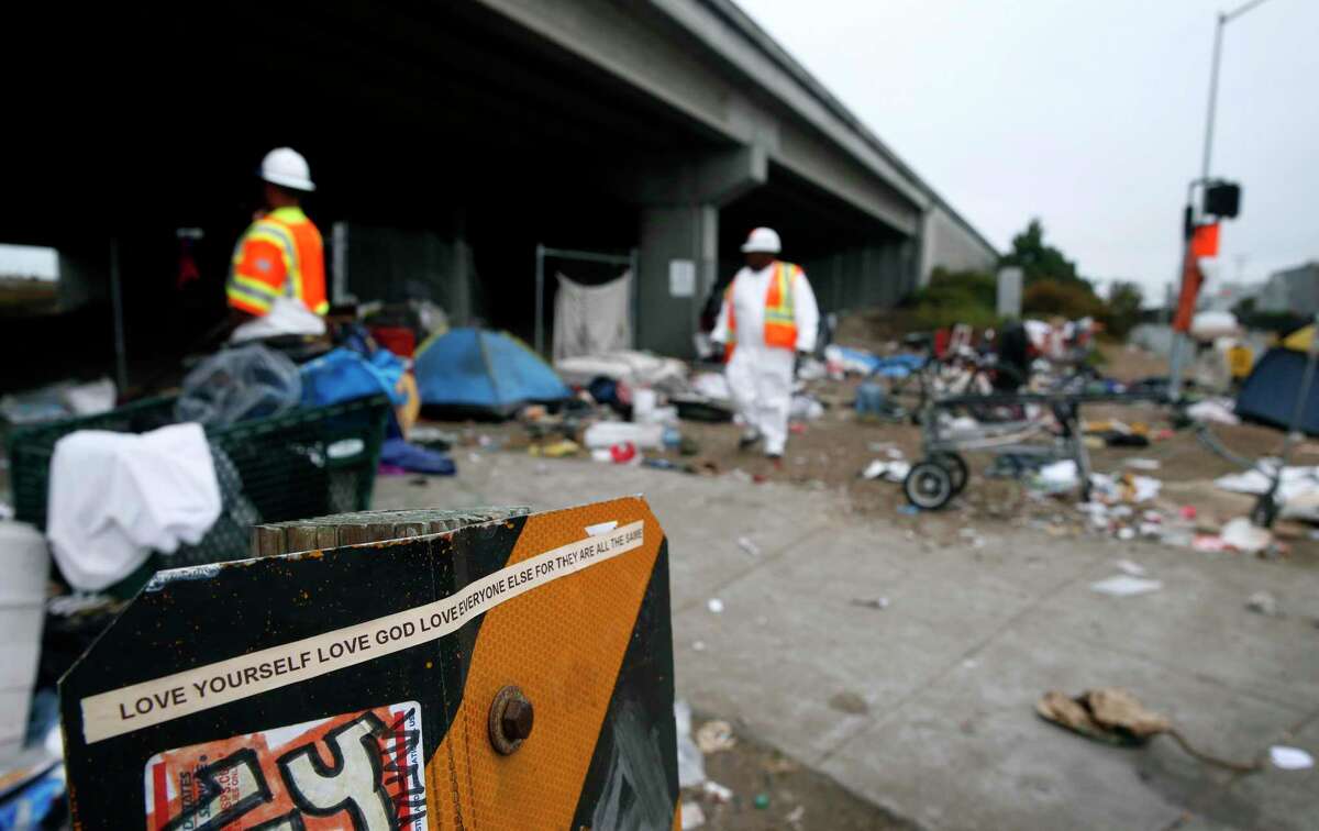 A Caltrans crew removes debris next to an Interstate 80 on-ramp after CHP officers cleared out a homeless encampment on Gilman Street in Berkeley, Calif. on Aug. 4, 2016.
