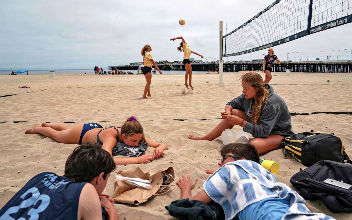 High school students relax on Santa Cruz Beach in 2020. Teens are more interested in listening to each other than to their parents, a Stanford study confirms.