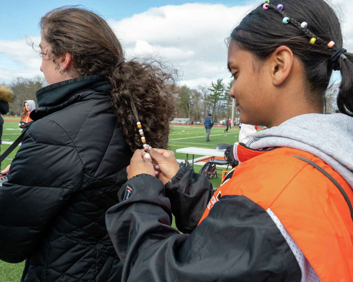 Mohonasen track runner Bonnieta Supaul puts beads in the hair of timer Emily Burns during a Colonial Council track meet at Mohonasen High School in Rotterdam on Wednesday, April 27, 2022. (Jim Franco/Special to the Times Union)