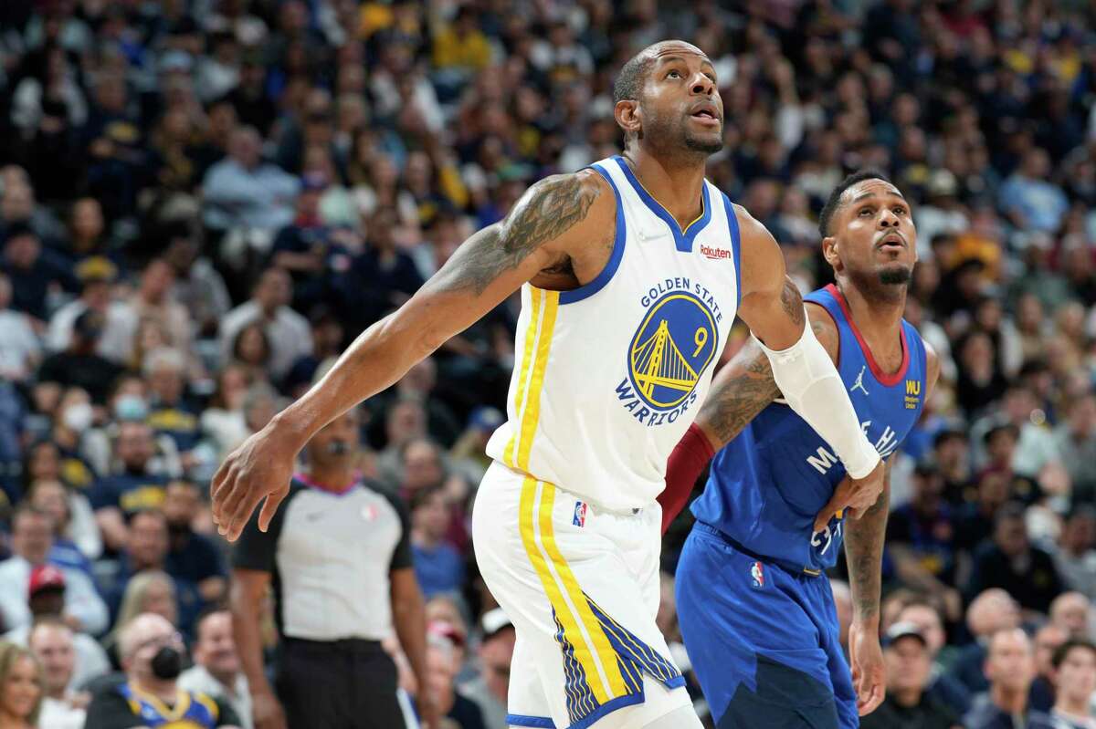 Warriors forward Andre Iguodala and Nuggets guard Monte Morris gaze at the ball in anticipation of a rebound.