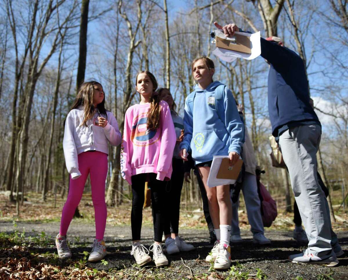 Fifth graders Ellie Kutai, left, Hannah Kutai, second left, and Emily Ward get help from Riverside School PE teacher Jay D'Andrea during an orienteering at Greenwich Public Schools Orienteering Adventure Days at Camp Seton in Greenwich, Conn.  Wednesday April 27, 2022. The two-decade tradition is designed to give fifth-grade students the opportunity to meet and interact with students who will be in their sixth-grade class in middle school next year.  The one-day camp included fun team-building activities like orienteering, rock climbing, rope balancing, bean bag tossing, ladder ball, and more.
