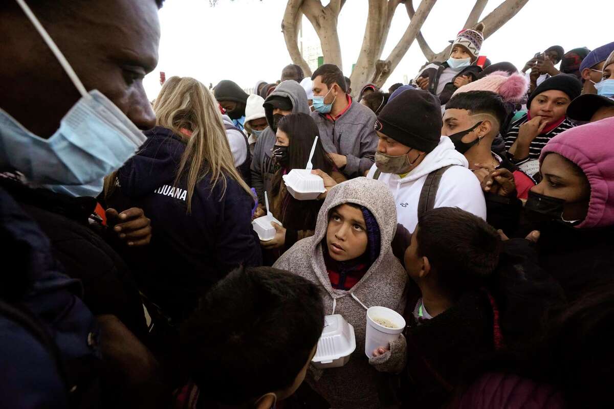 FILE — In this Feb. 19, 2021 file photo asylum seekers receive food as they wait for news of policy changes at the border, in Tijuana, Mexico. (AP Photo/Gregory Bull, File)