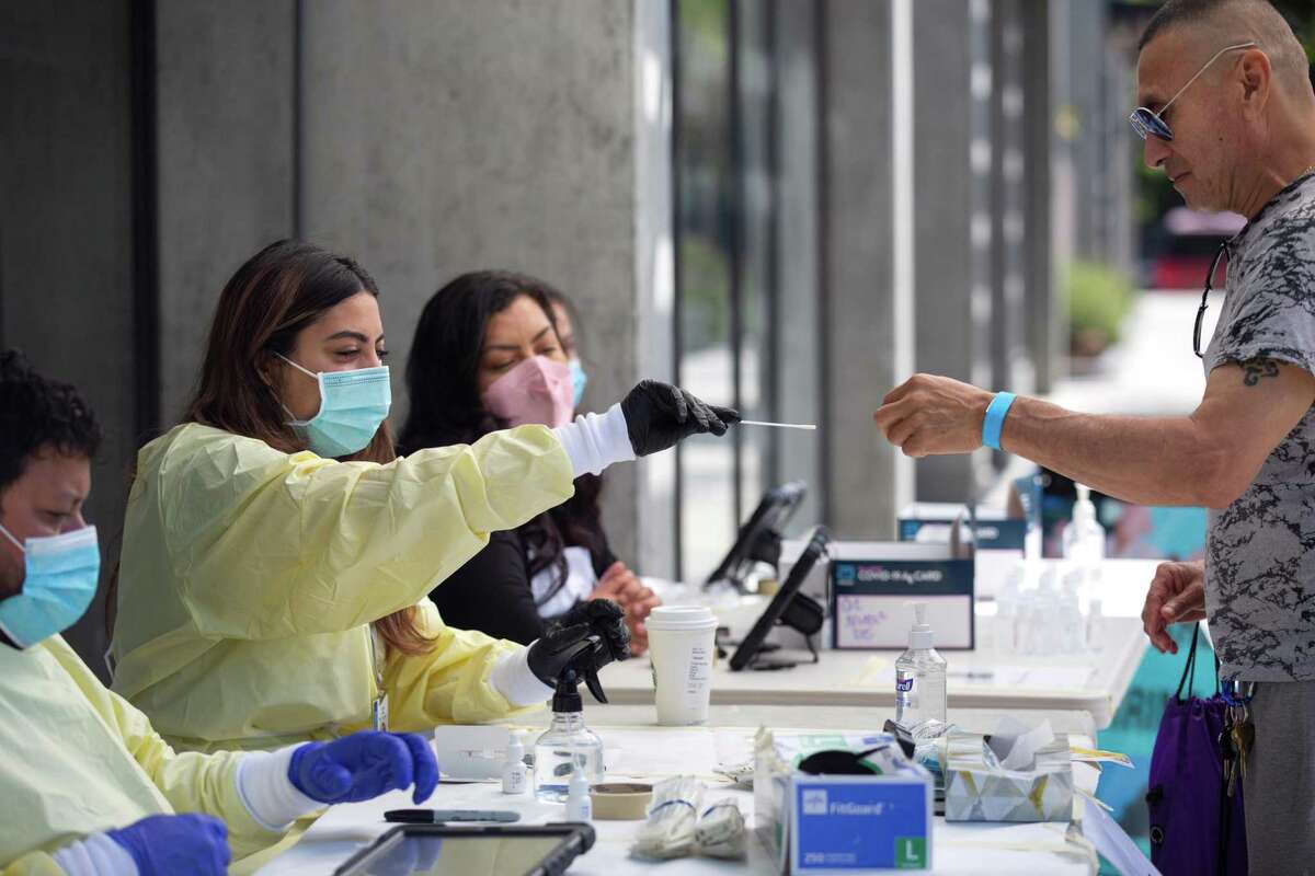 Jose Contreras of San Francisco, is getting COVID test, assisted by test administrators from Safer Together, during the "Vidas Saludables" Community Health and Wealth Fair hosted by the Mission Economic Development Agency in Chan Kaajal Park in San Francisco, Calif. on Saturday, April 23, 2022.