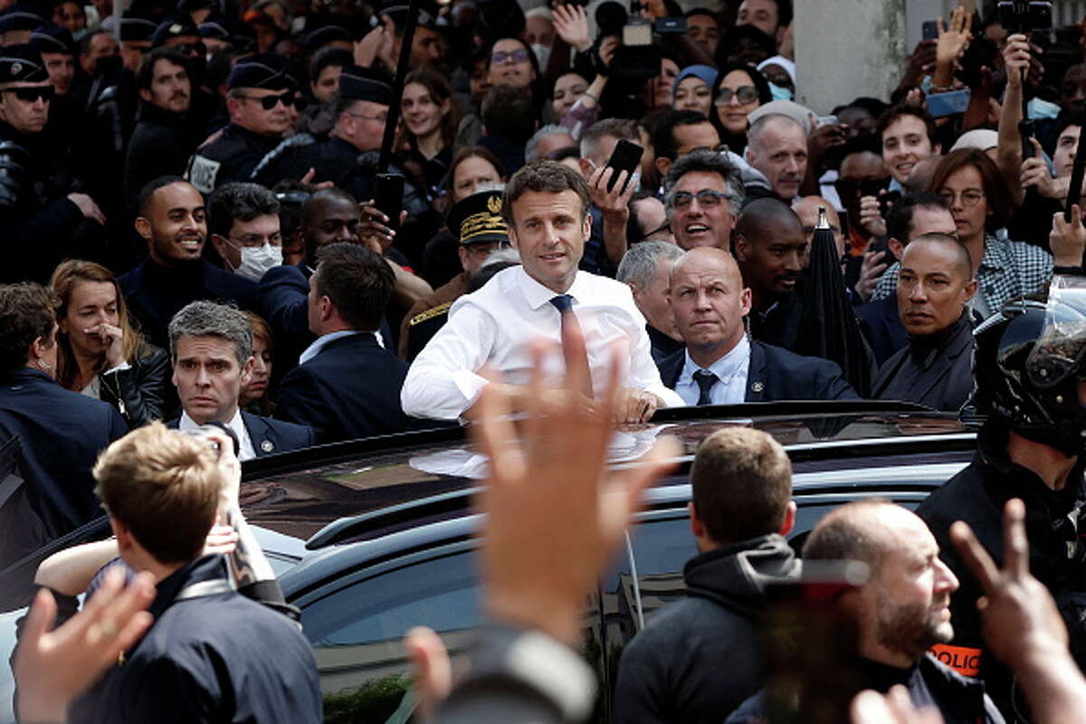 French President Emmanuel Macron is waved at by residents as he leaves after a visit at the Saint-Christophe market square in Cergy during his first trip after being re-elected president.