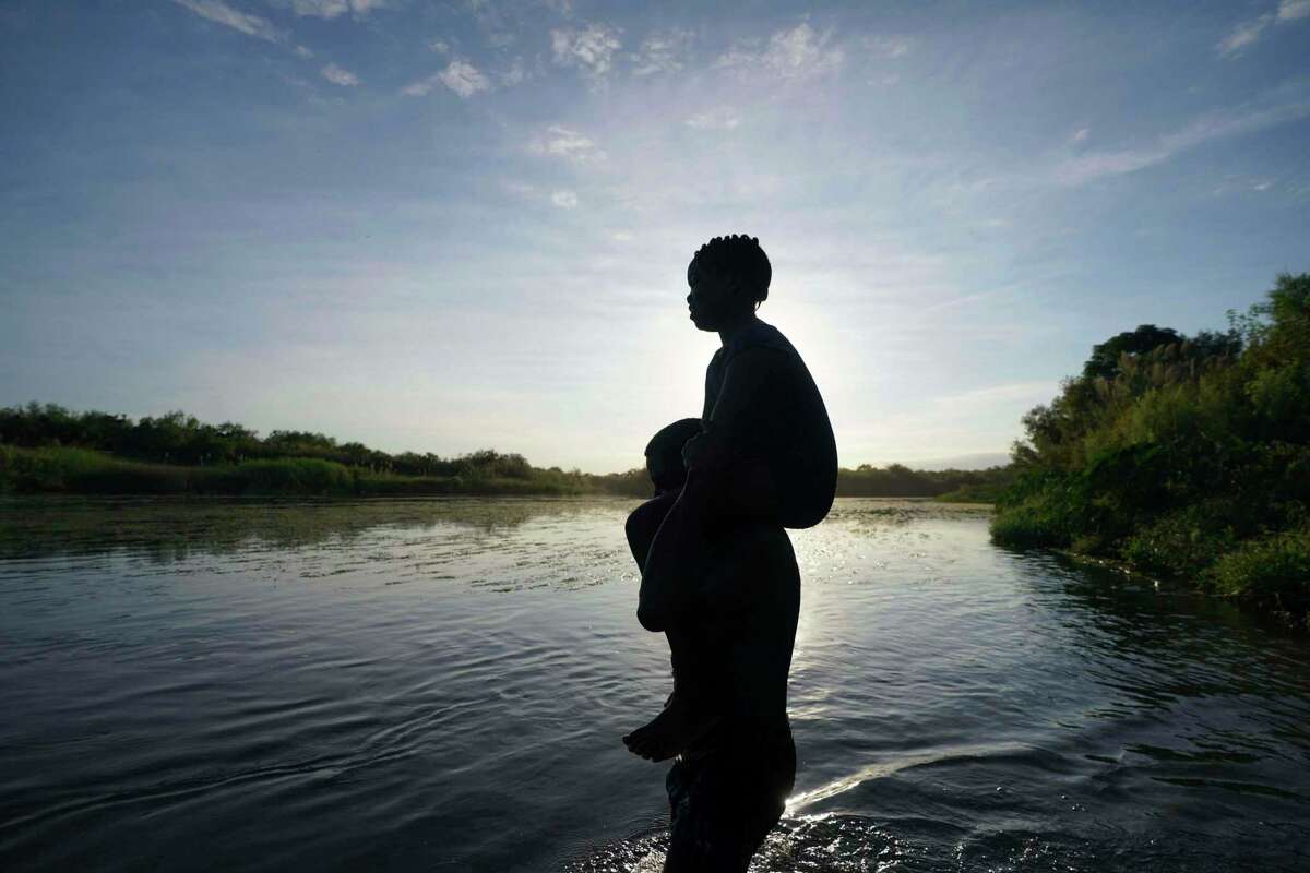 A father carries his daughter over the Rio Grande river toward Del Rio, Texas, from Ciudad Acuna, Mexico, Sept. 22, 2021. A Texas National Guard member who drowned on the U.S.-Mexico border was not wearing a flotation device, and had not been issued one, when he jumped in the Rio Grande to help a migrant who was struggling to swim across, state officials said Wednesday, April 27, 2022.