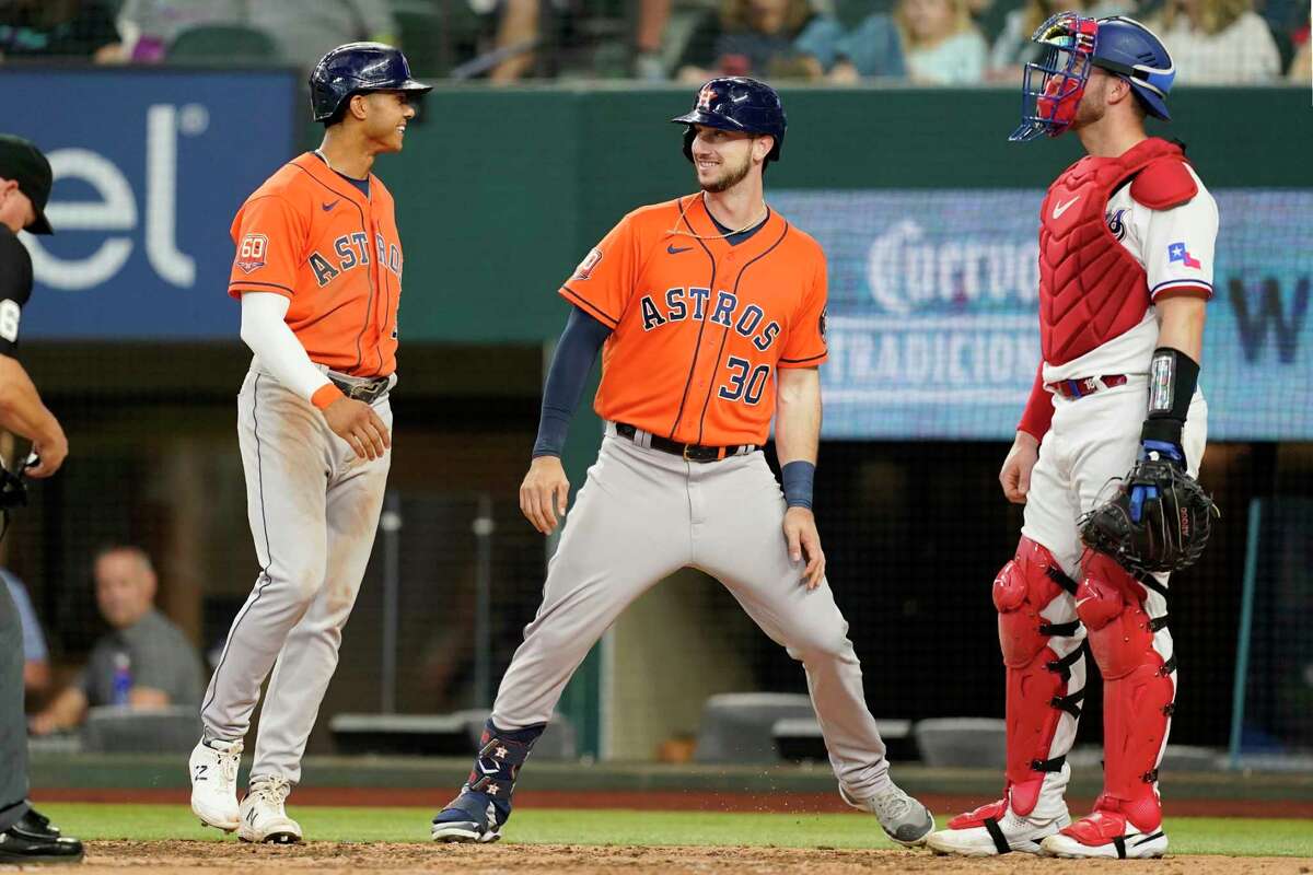 Houston Astros' Jeremy Pena, left, and Kyle Tucker (30) celebrate in front of Texas Rangers catcher Mitch Garver, right, after Tucker hit a two-run home run that also scored Pena in the eighth inning of a baseball game, Thursday, April 28, 2022, in Arlington, Texas. (AP Photo/Tony Gutierrez)