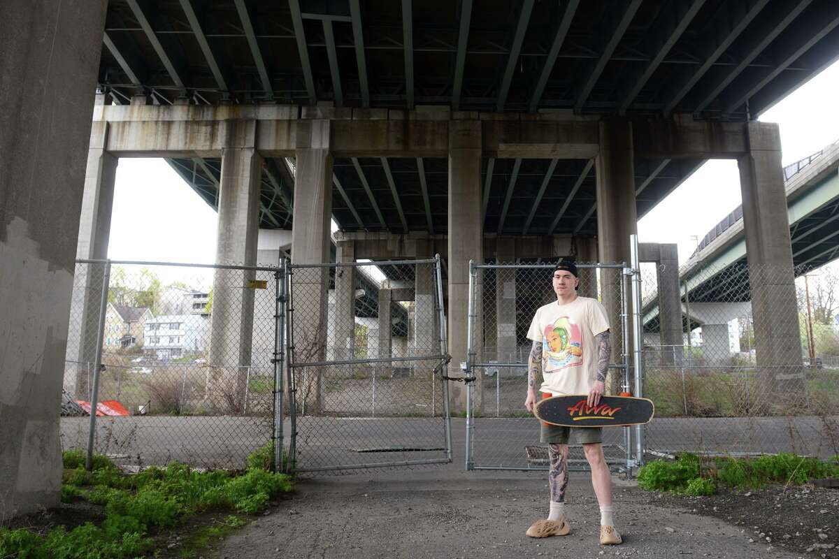 Jim Mazzadra poses in front of the vacant property under the Rt. 8 Commadore Hull Bridge, in Shelton, Conn. April 27, 2022. Mazzadra is leading efforts to rebuild the skate park that used to stand on the property.