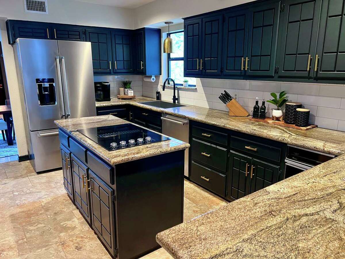 During the kitchen renovation, the couple painted the cabinets black, removed the popcorn ceiling and redid the large soffits. They kept the original black, brown and tan granite countertops.
