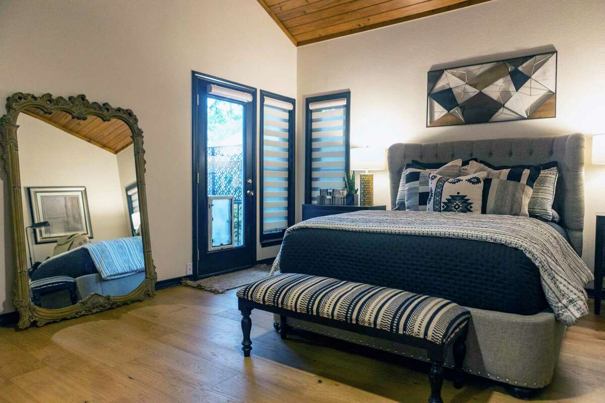 The owner’s suite bedroom has a sloped wood ceiling like the one in the living room. The couple replaced old-fashioned drapes with zebra shades.