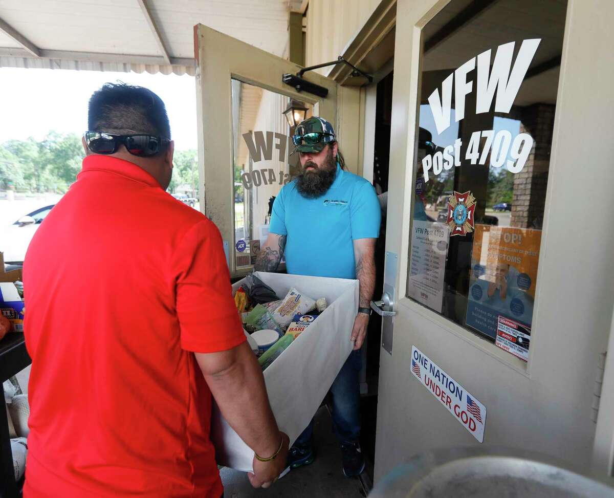 Bubba Jacobs, right, and Michael Davila carry a box of food to be sorted and weighed as volunteers with Keep US Fed Montgomery County, the Texas Veterans of Foreign Wars District 17 & Post 4709 gathered 554-pounds of food to donate to Camp Valor and Pilgrim Rest Baptist Church’s food pantry, Wednesday, April 27, 2022, in Conroe.